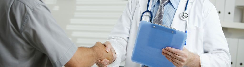 A male doctor stands in front of his patient, greeting him