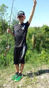 A young boy holds up a fish he just caught