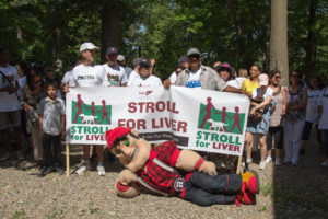 A group of Stroll participants hold the Stroll for Liver banner. They are joined by a lumberjack mascot