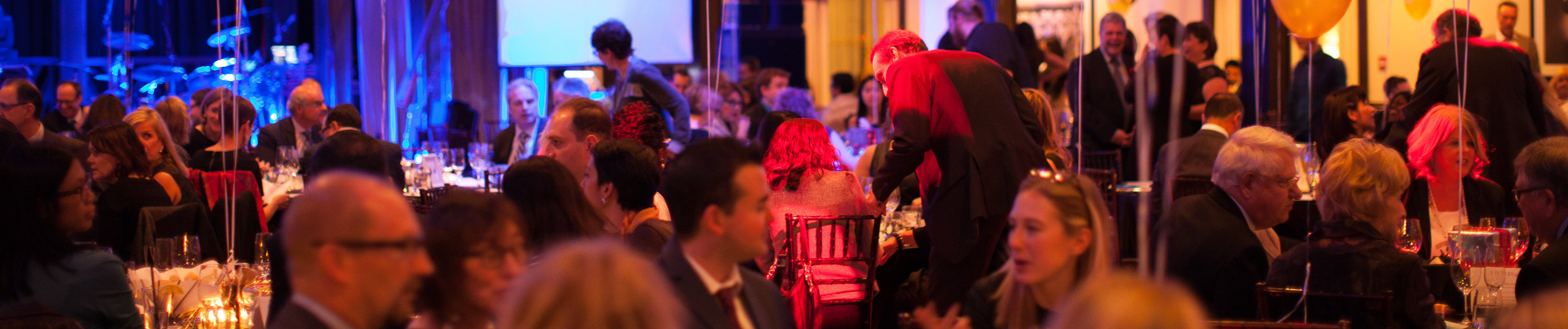 Une salle emballée au gala de Toronto, avec des personnes assises à la table et d'autres mains debout et serrées