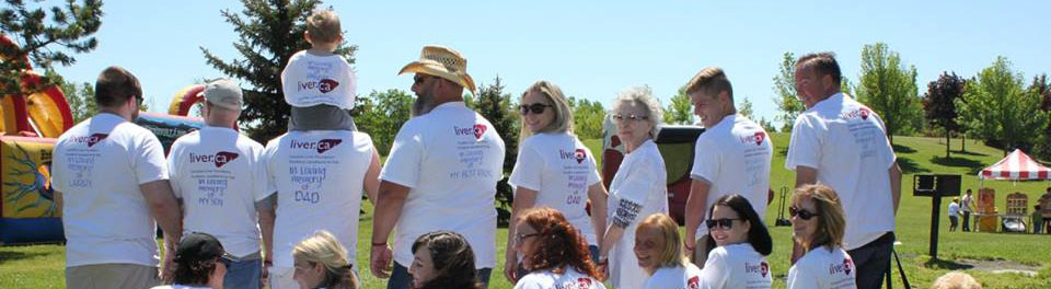 A group of Stroll for Liver participants with their backs to the camera, wearing white shirts with the Liver.ca logo on them