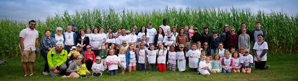 A group of Stroll for Liver participants pose for a group photo in front of a field