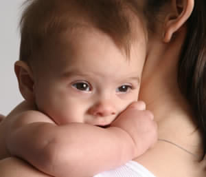 A closeup image of a baby holding on to a mother's shoulder