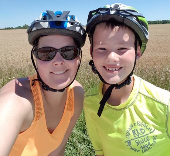 Lorraine and Zac riding bikes, wearing bike helmets. 