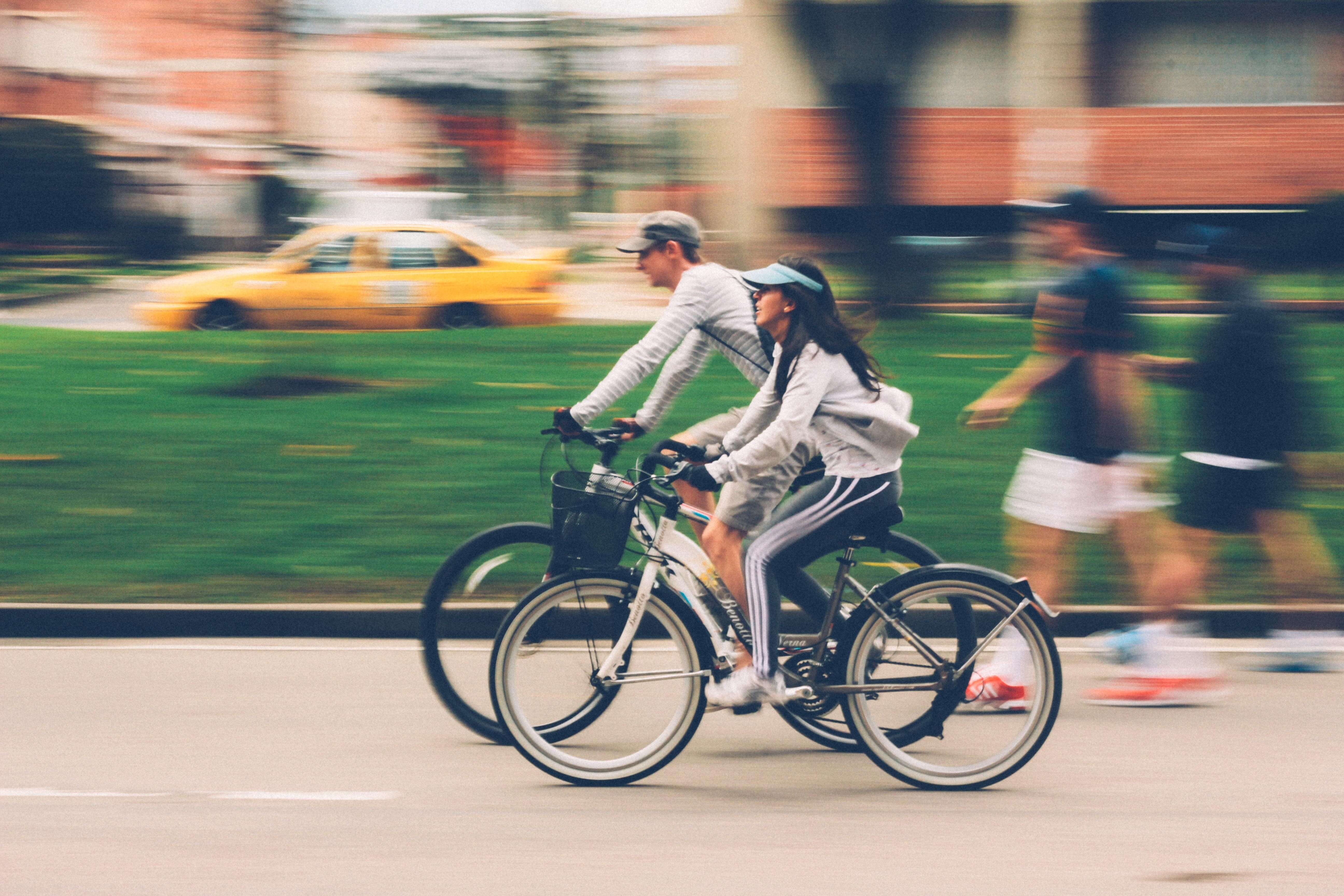 A man and woman ride bikes at the same speed down a bike or walking path. 