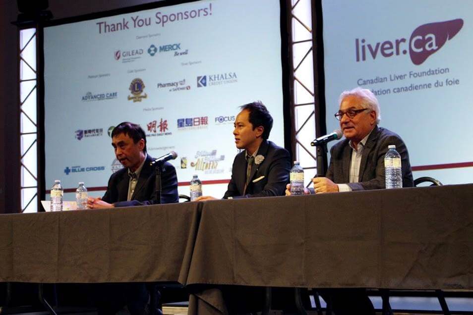 Three doctors are pictured during one of the Forum's Q&A sessions. They sit at a desk on stage with microphones and water bottles in front of them. Just behind them, project screens have the CLF logo and other sponsor logos displayed.