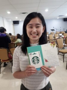 Andrea poses with a thank you card after conducting a informational presentation on hepatitis and liver disease at an Asian senior's home. 