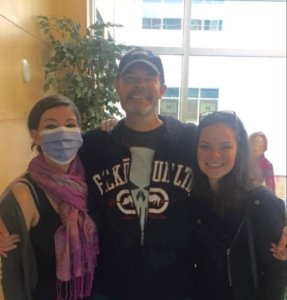 A woman wearing a mouth cover, her dad and sister
