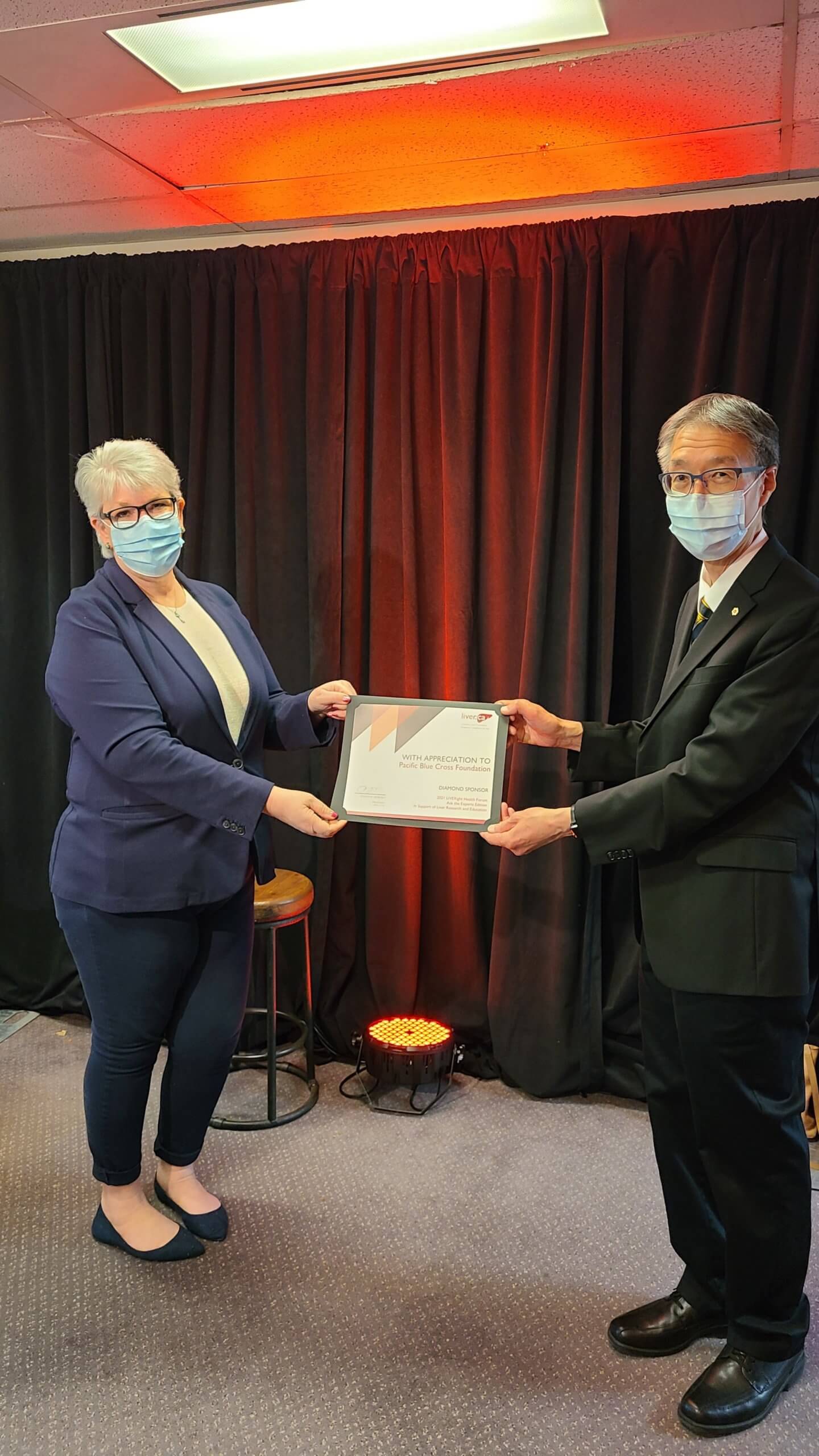 Pacific Blue Cross representative receiving certificate from Dr. Eric Yoshida 